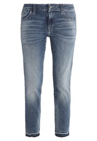 Jeans de denim ajustados en azul con un ligero desgaste, marcas de arrugado, pequeñas imperfecciones y dobladillos deshilachados.