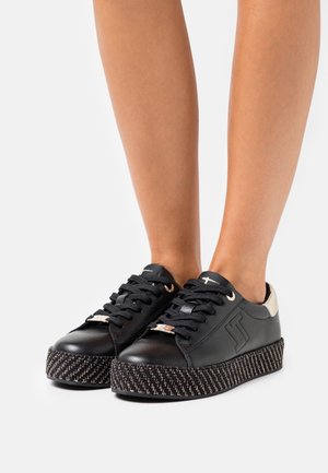 Zapatos de cuero negros con un tacón de acento metálico y una suela de plataforma gruesa trenzada, con cordones negros y ojales en tono plateado.