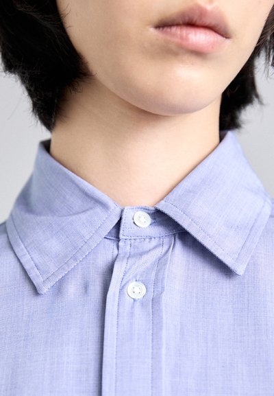 Light blue collared shirt with a textured fabric, featuring a two-button closure and sharp collar points.