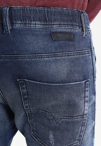 Mörkblå denimjeans med en urtvättad effekt, med en bakficka med ett distinkt sömnadsmönster och en märkesläderlapp.