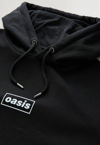 Zwarte hoodie gemaakt van katoen met een zachte textuur, met een witte rechthoekige logo met "oasis" en een trekkoord met metalen tips.