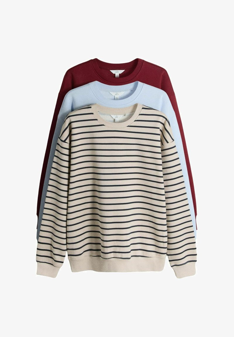 Drie crewneck truien opgestapeld; de voorkant is beige met zwarte horizontale strepen, de middelste is lichtblauw en de achterkant is donkerrood.