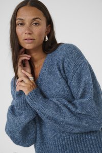 Kék kötött pulóver V-kivágással, laza fazonnal és bordás ujjaknál. Texturált fonalból készült, puha, kényelmes megjelenéssel.