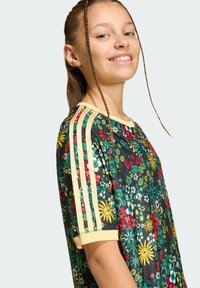 Μαύρο μπλουζάκι με λουλουδένιο σχέδιο σε πράσινες, κίτρινες κα ι κόκκινες αποχρώσεις, με μπεζ ρίγες στα μανίκια και στρογγυλή λαιμόκοψη.