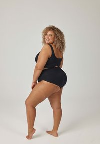Czarny dwuczęściowy strój kąpielowy z bezrękawnym topem i majtkami z wysokim stanem. Gładka faktura z wycięciami po bokach i szerokimi ramiączkami.