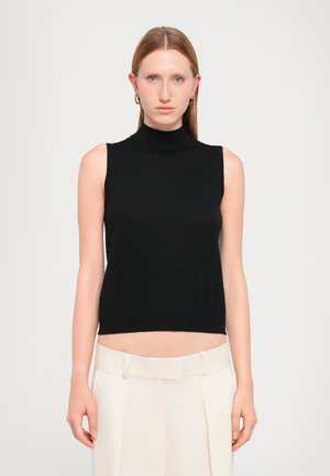 Black sleeveless turtleneck top made of a smooth fabric, featuring a fitted design that ends above the waist, paired with pale beige tailored trousers.