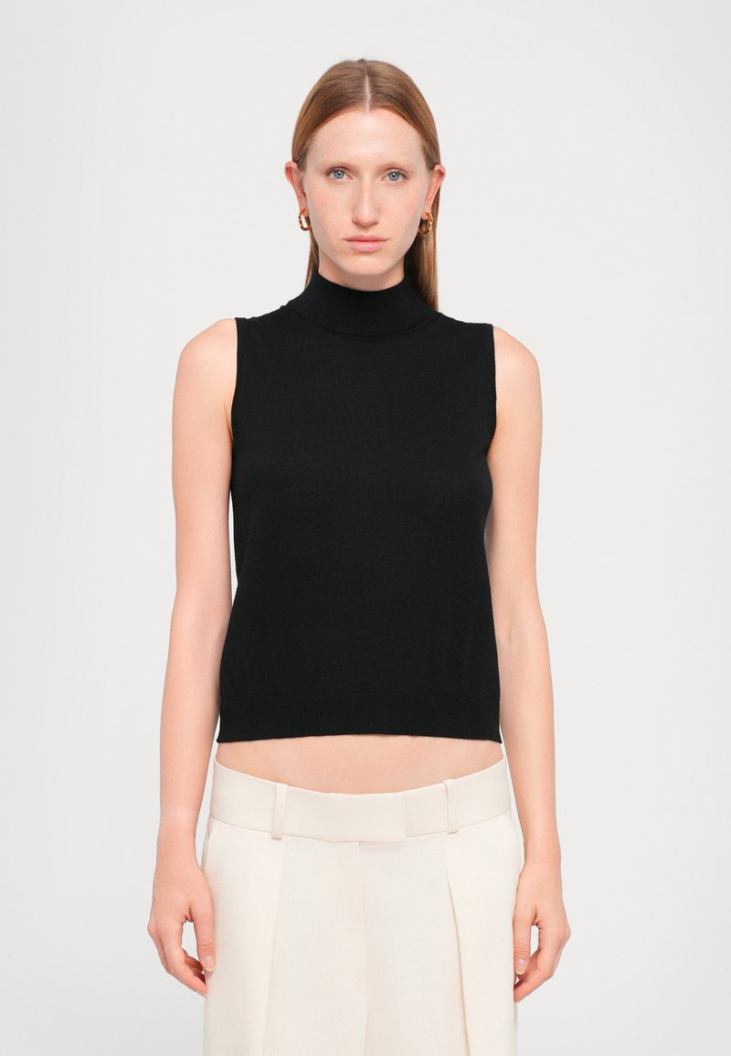 Must have mustrisöötuga must tanktop, mis on valmistatud siledast kangast, sujuva disainiga, mis lõppeb vöö kohal, koos heledate beezide kohandatud pükstega.