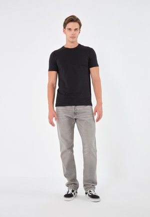 Svart t-shirt med kort ärm i klassisk passform, matchad med ljusgrå jeans med en minimalistisk design, samt svarta och vita sneakers.
