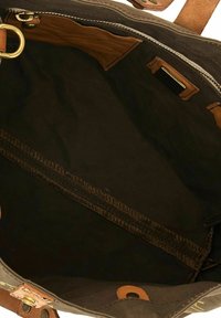 Interno della borsa tote in tela nera con dettagli in pelle marrone; presenta una tasca con zip e una tasca interna liscia e foderata.