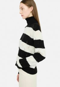 Melnā un baltā svītrainā adītā turtlenecka džemperis, ar teksturētu rakstu un ribotām piedurknēm, ar pieguļošu siluetu un mīkstu materiālu.