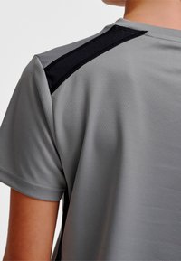 Szary sportowy T-shirt z krótkimi rękawami, gładką fakturą oraz czarnymi siateczkowymi wstawkami na ramionach dla lepszej wentylacji.