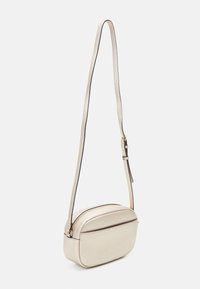 Metalická zlatá crossbody kabelka zaobleného tvaru, texturovaný materiál, úzký nastavitelný popruh a zipové uzavření.