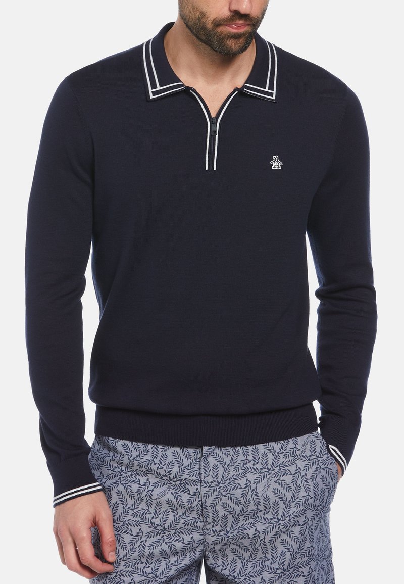 Pull en marine avec col zippé et détails à rayures blanches. Présente un petit logo brodé sur la poitrine. Fabriqué en tissu tricoté.
