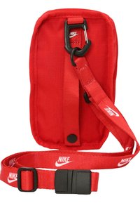 Červený nylónový pouch s textúrovaným povrchom, vybavený čiernym klipom a nastaviteľným popruhom. Na popruhu a vpredu zobrazuje biele logo Nike.