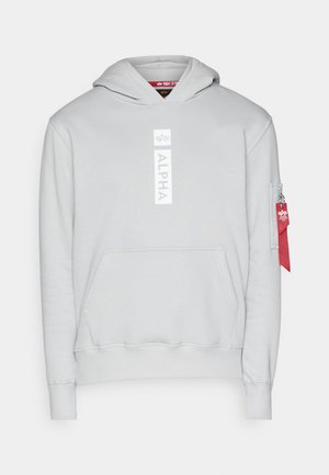 Hellgrauer Hoodie mit Kängurutasche, Kapuze mit Kordelzug, weißem "ALPHA"-Logo und einer Reißverschlusstasche am Ärmel mit einem roten Etikett.