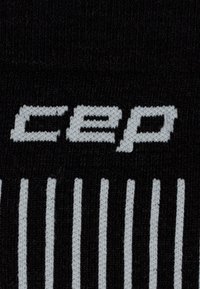 Schwarze Sportsocke mit einem auffälligen weißen "cep"-Logo und vertikalen weißen Streifen. Hergestellt aus strukturiertem Stoff für Komfort und Passform.