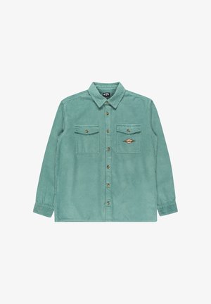 Chemise en velours côtelé vert à manches longues, avec fermeture à boutons, deux poches avant et un patch décoratif sur la poitrine gauche. Tissu texturé.