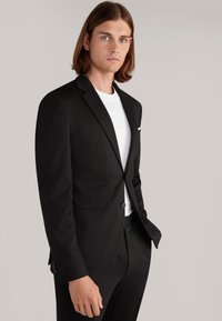 Schwarze maßgeschneiderte Sakko mit Reverskragen, einreihigem Verschluss, zwei Fronttaschen und glatter Textur, getragen über einem weißen T-Shirt.