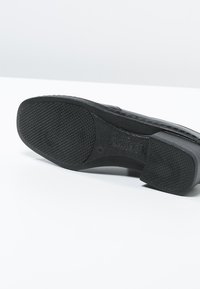 Black rubber shoe sole with textured grip, featuring a smooth, curved design and subtle branding along the arch.