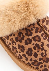 Chausson imprimé léopard avec un doux bord en fausse fourrure, couleurs marron et beige, couture le long du bord, et base texturée pour une meilleure adhérence.