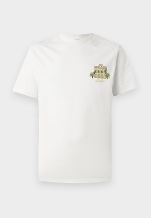 T-shirt en coton blanc avec un petit motif brodé représentant un bâtiment entouré de palmiers. Manches courtes et col rond.