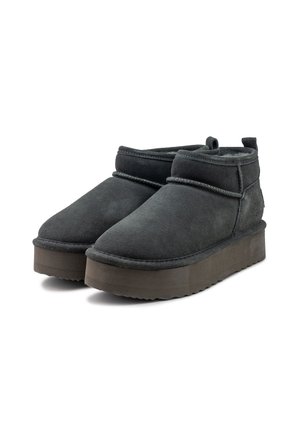 Zwarte suède enkelboots met een ronde neus, minimalistisch ontwerp en een dikke platformzool. Heeft een zachte binnenkant en stikseldetails.