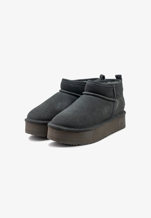 Stivali alla caviglia in camoscio nero con punta arrotondata, design minimalista e suola piatta spessa. Presentano un interno morbido e dettagli di cucitura.
