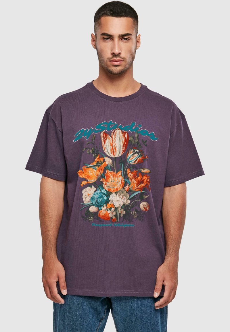 Lilla bomulls oversized t-skjorte med en fargerik blomstertrykk i oransje, blå og hvite blomster, som viser intrikate detaljer og tekstur.