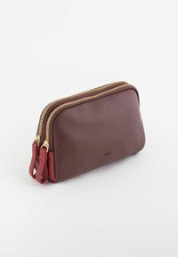 Portefeuille en cuir zippé de couleur bordeaux foncé avec une finition texturée, ornée de zips dorés et d'un accent rouge sur le côté. Design compact.