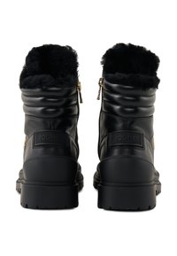 Černé kožené kotníkové boty s umělou kožešinou, prošívaným designem, bočními zipy a texturovanou gumovou podrážkou. Na zadní straně se nachází značka.
