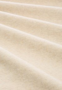 Beżowa tkanina o subtelnej teksturze, z miękkimi, gładkimi włóknami i delikatnymi fałdami. Jasny kolor z drobnymi różnicami w odcieniach.