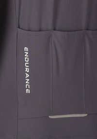 Tissu gris foncé avec trois poches cousues et texte vertical blanc "ENDURANCE" sur la poche de gauche.