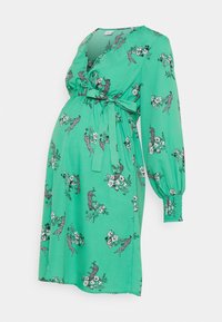 Grön omlottklänning med blommönster och leopardtryck, långa puffärmar och bälte i midjan. Tillverkad av lättviktsmaterial med en slät textur.