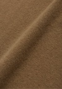 Tissu marron à texture lisse, présentant un tricot fin et des variations subtiles de teinte, créant un aspect doux et homogène.