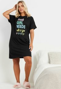 Svart nattklänning med korta ärmar, prydd med färgglad text och hjärtan. Mjukt tyg, knälång, i perfekt kombination med rosa fluffiga tofflor. Enkel design.