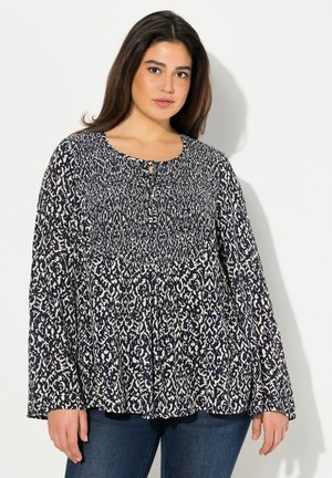 Blouse à motif bleu marine et crème avec des manches longues, un col rond et un détail en trou de serrure à l'avant. Tissu doux et léger avec un design fluide.