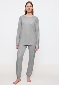 Vaaleanharmaa pyjama-asuste, joka on valmistettu pehmeästä puuvillasta; pitkähihainen paita, jossa on kukkakirjontaa olkapäillä; löysät housut, joissa on joustavat hihat.