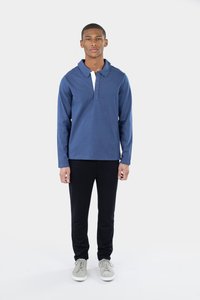 Marineblå langærmet polo med krave og en hvid stolpe, parret med sorte bukser og lysegrå sneakers på en neutral baggrund.