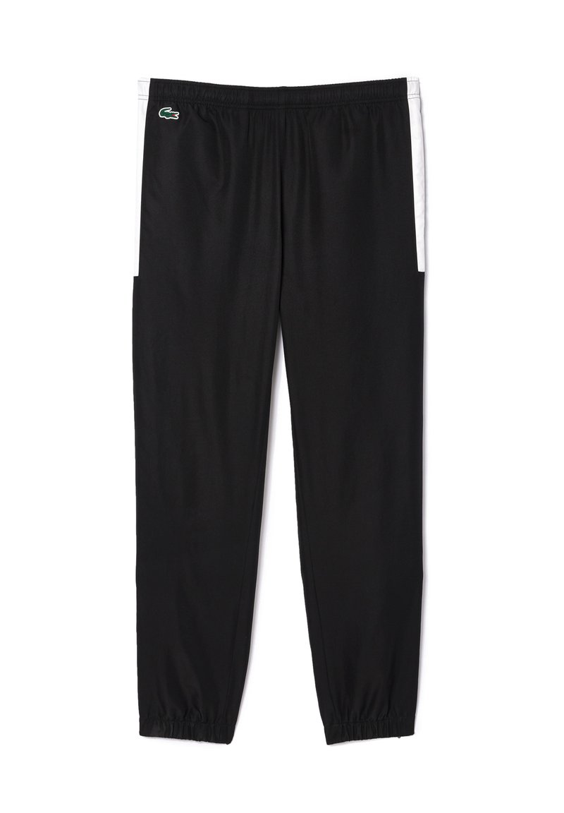 Pantalons de jogging en polyester noir avec taille élastique et poignets aux chevilles. Deux poches latérales avec accents blancs. Logo Lacoste sur la hanche gauche.