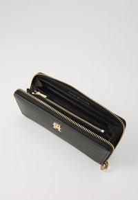 Black leather wallet with a textured finish, zip closure, gold hardware, multiple card slots, and a visible brand logo on the front.
