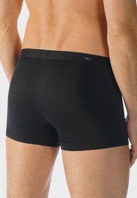Boxer-briefs noirs avec une ceinture élastique douce, un design ajusté et une texture lisse. Présentent un logo discret sur la ceinture.