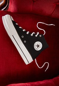 Czarne sportowe buty za kostkę na czarnej podeszwie z białą gumą, przelotkami i noskiem; posiadają charakterystyczną naszywkę z logo w kształcie gwiazdy oraz białe sznurowadła.