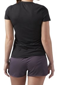 Svart kortärmad träningsskjorta kombinerad med mörklila shorts. Skjortan har en rund halsringning och en figursydd design.