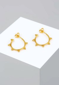 Boucles d'oreilles créoles en or avec de petites pointes de perles regroupées, espacées uniformément le long du bord extérieur, exposées sur un socle blanc.