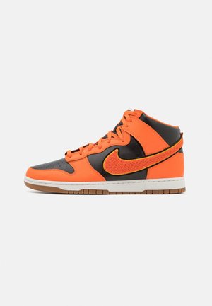 Sneakers alte in pelle arancione con dettagli neri. Presentano un logo Nike a forma di baffo testurizzato, una suola intermedia bianca e una suola in gomma.