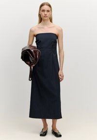Schulterfreies navy Midi-Kleid mit vertikalen weißen Nadelstreifen, taillierte Passform, glatte Textur, kombiniert mit einer dunkelburgunderfarbenen Lederhandtasche und schwarzen Ballerinas.