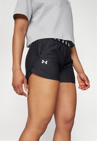 Svarta sportshorts med white logo, med ett elastiskt midjeband och slitsad nederkant för ökad rörlighet. Slät textur.