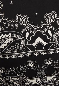 Tejido negro con intrincados patrones de paisley y flores en blanco, con bordes enrollados detallados y un grosor de línea variable para crear textura.