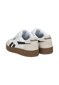 Białe i beżowe sneakersy Reebok z chropowatą cholewką z zamszu i skóry, czarnymi paskami oraz brązową gumową podeszwą.