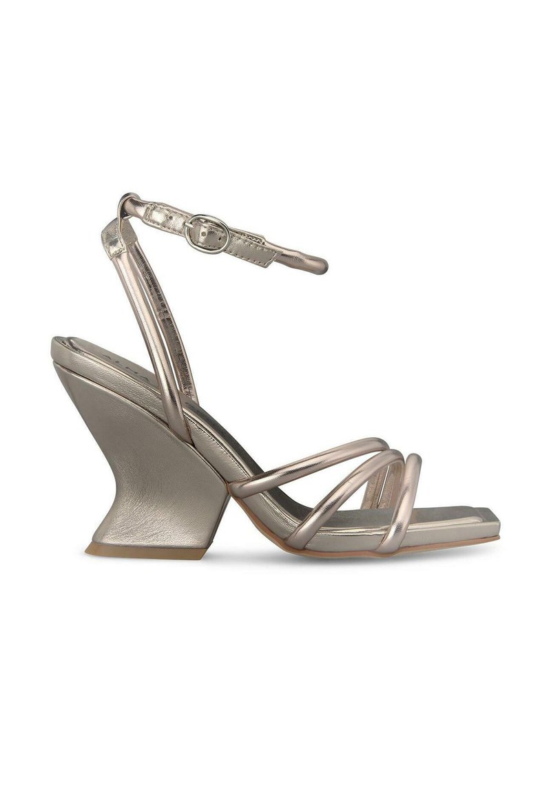 Sandales à talons hauts en or rose métallique avec un talon en coin angulaire, dotées de fines lanières croisées et d'une boucle de cheville ajustable.